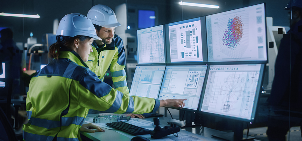 Industry 4.0 Modern Factory: Project Engineer Talks to Female Operator who Controls Facility Production Line, Uses Computer with Screens Showing AI, Machine Learning Enhanced Assembly Process stock photo